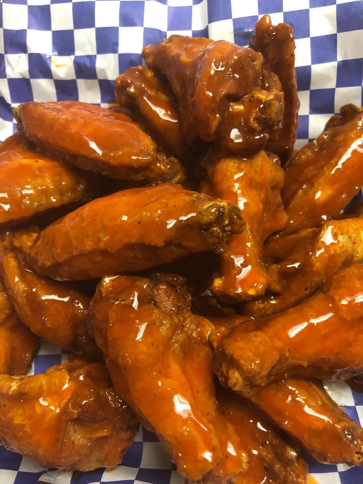 A pile of BBQ-glazed wings on blue check paper